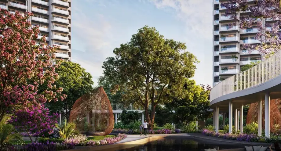M3M Forestia West apartment towers with curved skywalk and flowering trees