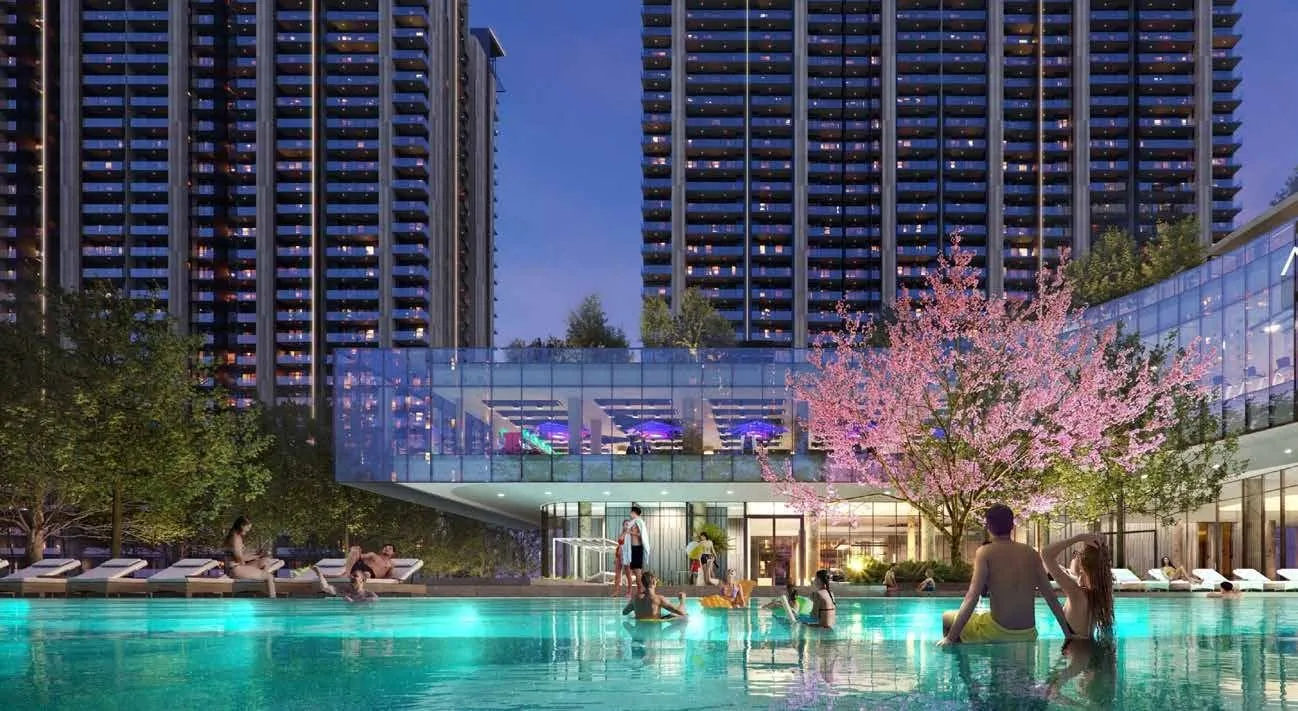 Illuminated clubhouse swimming pool with cherry-blossom landscaping at M3M Golf Hills at night